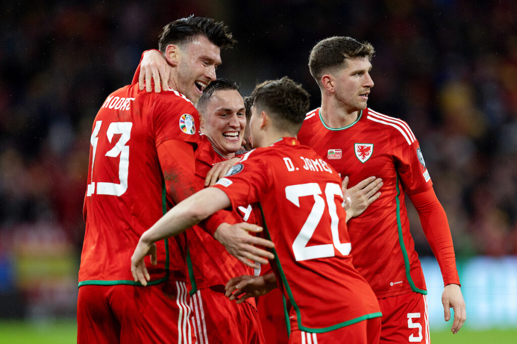 Wales' Kieffer Moore celebrates after scoring the team’s first goal with teammates Wales' Connor Roberts, Wales' Dan James and Wales' Chris Mepham during the Group D UEFA Euro Championship Qualifying between Wales and Latvia on the 28th of March 2023 at the Cardiff City Stadium, Cardiff, Wales