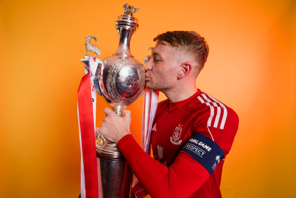 Connah's Quay Nomads John Disney celebrates with the Welsh Cup after winning the 2023/24 JD FAW Welsh Cup Final fixture between Connah's Quay Nomads F.C and The New Saints F.C at Rodney Parade, Newport, Wales