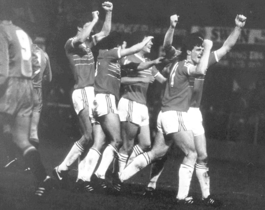 Mark Hughes celebrates with his Cymru teammates after scoring against Spain
