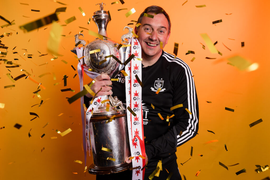 Connah's Quay Nomads coach Neil Gibson celebrates with the Welsh Cup after winning the 2023/24 JD FAW Welsh Cup Final fixture between Connah's Quay Nomads F.C & The New Saints F.C at Rodney Parade, Newport, Wales