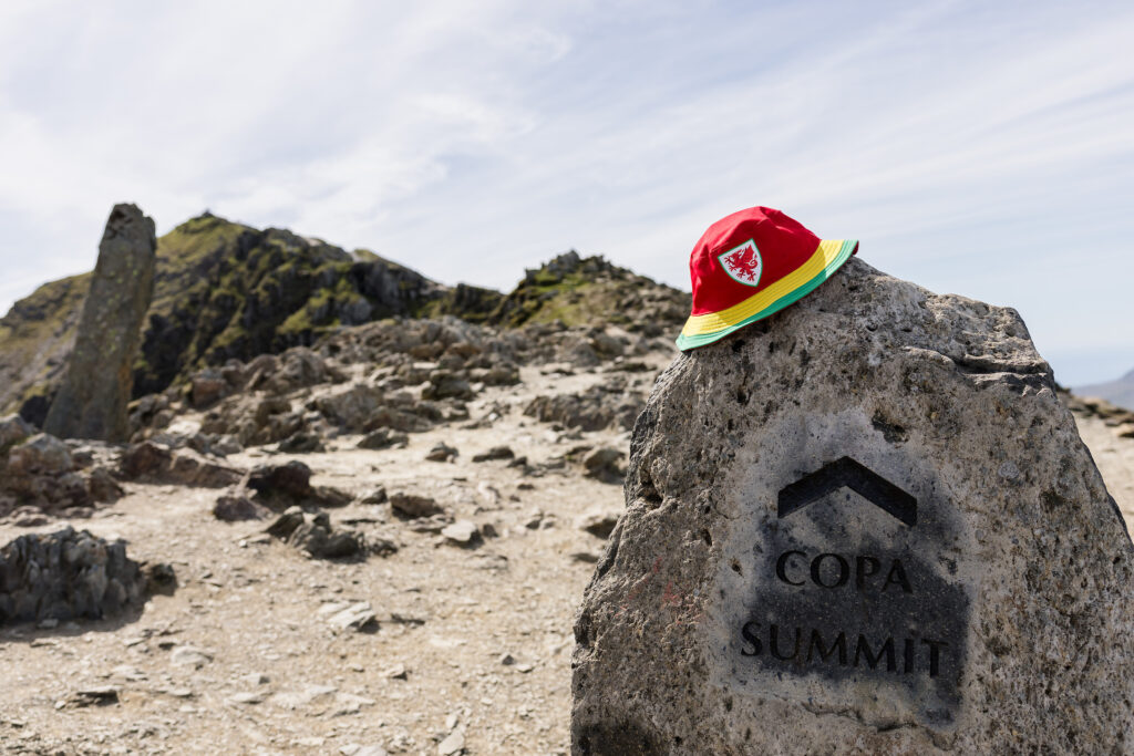 A Cymru bucket hat rests on the summit of Wyddfa, which is where Rhian Wilkinson will announce her squad for EURO 2025. 
