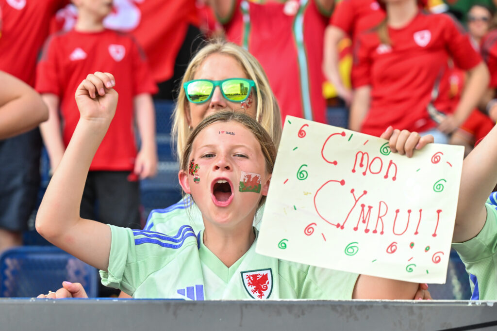 A young Cymru fan with a 'C'mon Cymru sign' at EURO 2025